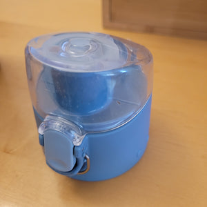 Close-up of blue lid, with blue button to open the clear top that covers the spout.