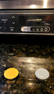 One appliance slider is showing its sticky part (yellow) and the other slider is showing the part that slides (white) on a marble countertop.