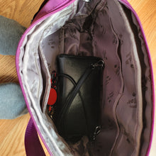 Load image into Gallery viewer, Inside view of the bag, showing how small Lisa&#39;s black credit card/wallet purse looks in the bottom of the bag. Several pockets are visible and the lining says Jiel Shi.
