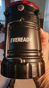 Side of the black body of the camping lantern showing a metal handle that's folded down, a black button about the size of a thumb for the flashlight, and "eveready" branded in the middle.