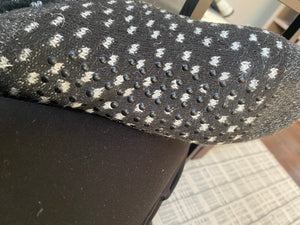 Close-up of the sock. Round, black grippers are visible, as are the white dotes woven into the black sock.