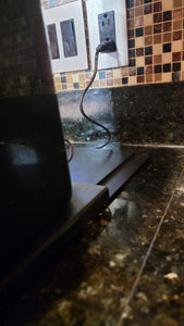 A view of the black caddy device on which the coffee maker rests. The caddy is pulled forward and so the tracks behind the coffee maker are visible.
