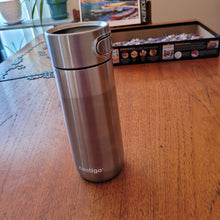 Load image into Gallery viewer, Side view of the silver Contigo mug. The mug says contigo at the bottom. The valve button is visible from the side.
