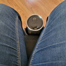 Load image into Gallery viewer, View of a person sitting in the wheelchair, looking down at the cup holder which sits directly against the front of the seat and between their legs. A contigo travel mug is sitting in the cup holder.
