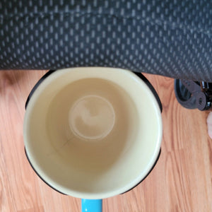 Top down view of a mug in the holder. The handle of the mug sticks out through one of the slits in the holder.
