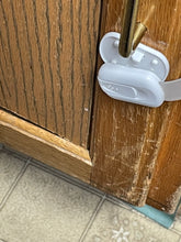 Load image into Gallery viewer, A white &quot;lock&quot; is attached to one side of a wooden cabinet. The one part of the lock is detached from the base of the lock.
