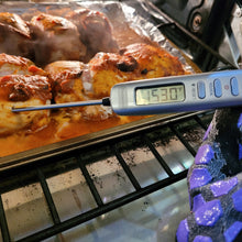 Load image into Gallery viewer, A gray meat thermometer is inserted into chicken cooking in the oven. A pretty large digital screen on the thermometer reads 153.0 F. Three buttons are visible: Power; Hold/CAL; light/Reset. 
