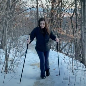 Sarah wears the Kahtoola NANOspikes and uses Montem hiking poles on snowy path in the woods.