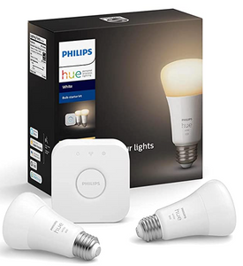 Black box with a light bulb on it and the words Philips and Hue. In front of the box are two lightbulbs and a small white square "hub" that says Philips on the front.