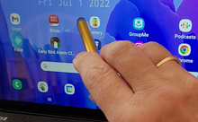 Load image into Gallery viewer, A person is using the stylus to press a button on the touch screen of a tablet, which shows a blue background and many icons.
