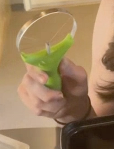 A person is holding the avocado slider, which has a neon green handle and then silver blades in the shape of a pizza.