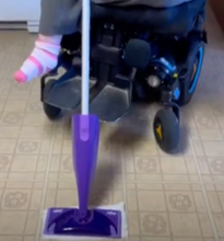 Load image into Gallery viewer, The purple Swiffer WetJet head is visible on the floor. A power wheelchair is in the background.
