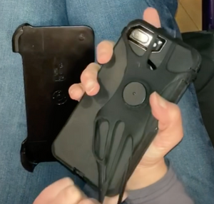 A person is stretching the rubber holder around the phone. This piece helps connect the phone to the mount.