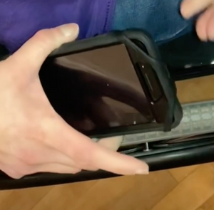 A person is slipping the cell phone into the mount on their wheelchair.