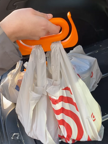 A person is holding the handle, which has plastic bags on it, which are being removed from a car trunk.