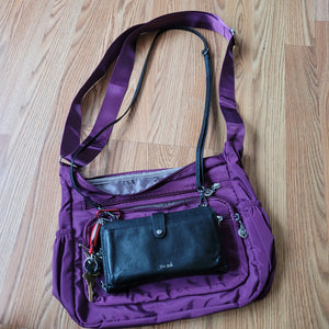 Small purse sitting on top of purple bag to show size comparison.