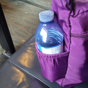 Side view of the bag, which has an elastic pocket that fits a standard plastic water bottle.