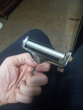 Load image into Gallery viewer, A person is holding the handle of the metal cheese roller. It does not extend the entire length of the palm of their hand.
