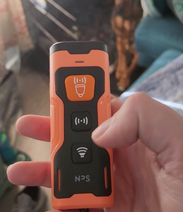 Close up of the three buttons on the orange and black device. The top one is orange, the bottom two are black. Each has a different symbol.