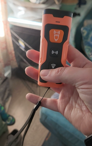 Another view of the black and orange device in a person's hand.