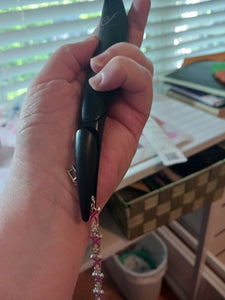 A person is using a black thin device to clasp the end of a bracelet