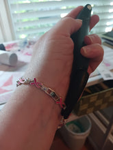 Load image into Gallery viewer, The black device is clasping one end of a bracelet that is now fastened around their wrist.
