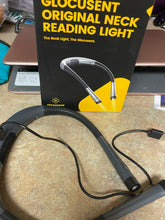 Load image into Gallery viewer, The gray neck lamp is sitting on a counter with the charging cord plugged into it. The arms of the lamp are flexible. The product box is sitting behind it and says &quot;Glocusent Original Neck Reading Light&quot;
