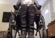 Load image into Gallery viewer, A person is seated in a wheelchair but we only see the lower half of their body. They are wearing black boots with black leg gaiters that go from the boot to below the knees.
