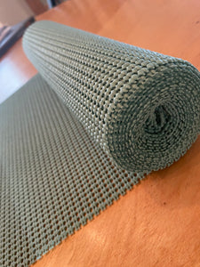 A roll of teal shelf liner unrolling on a wooden table.