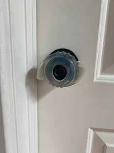 Clear plastic door knob grip with small "wings" on either side and texture for extra grip.