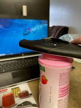 Load image into Gallery viewer, The black jar opener on top of a pink childproof vitamin bottle. 
