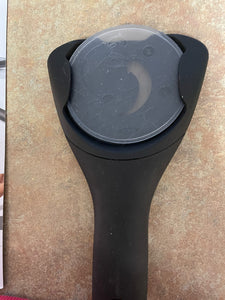 Black jar opener securely holding the rubber base pad on the back of it. 
