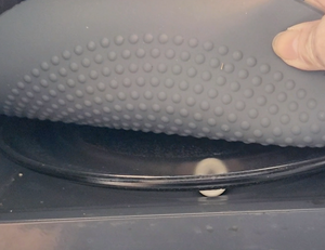 The side of the gray microwave mat is pulled up, exposing small gray nubs that create additional grip.