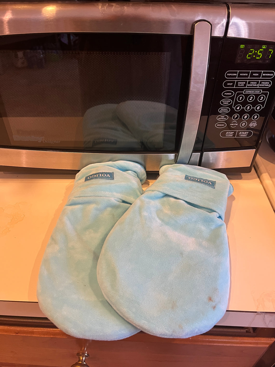 Light blue voligo mitts sitting on a counter in front of a microwave.