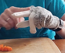 Load image into Gallery viewer, The person is wearing a glove on one hand and pointing out the three reinforced fingers (thumb and first two fingers) of the glove, which are white as compared to the rest of the glove which is gray.
