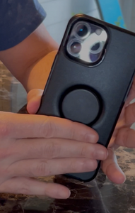 Black Otter + Pop Symmetry Phone Case being held by someone, showing the pop socket on the case.