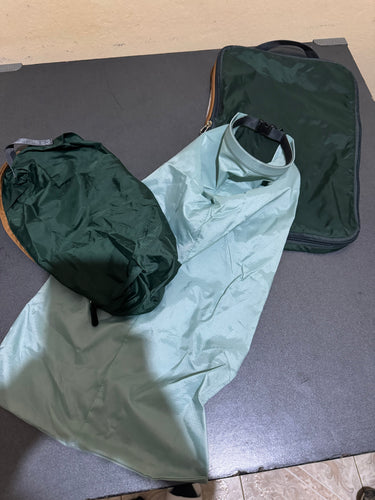 Two dark green compression cubes laying on a table, with a larger light blue laundry bag laid out in the middle.