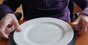 A dinner plate sits on top of a gray microwave mat on a wood table.