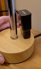Load image into Gallery viewer, A side view of the base, showing a charger plugged into the base of the lamp.
