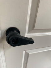Load image into Gallery viewer, Sammons Preston black rubber extension handle creates a lever on a black round doorknob, on a white door. The key hole is hard to see because it is also black, but there is an opening in the handle for the keyhole.
