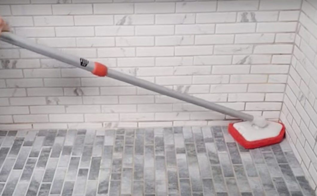 Scrubber pole is extended and reaching into the corner of the shower.