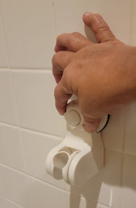 A person's hand is turning the knob on the shower holder, used to tighten it after pushing the button a number of times.