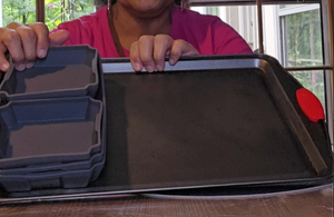 Karen has stacked all the silicone pans inside of each other on one side of the cookie sheet.