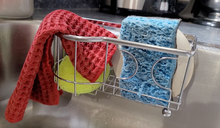 Load image into Gallery viewer, Simple Houseware silver kitchen sink sponge holder with a blue dish sponge, a yellow round sponge, a white drain cover, and a red dish cloth hanging over the edge. 
