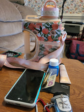 Load image into Gallery viewer, The contents that the mesh pocket of the water bottle normally holds is laying on a table in front of it. There is a phone, credit card, keys, lotion, sanitizer, and medicine. The long strop of the water bottle is visible, as is the large handle of the bottle.
