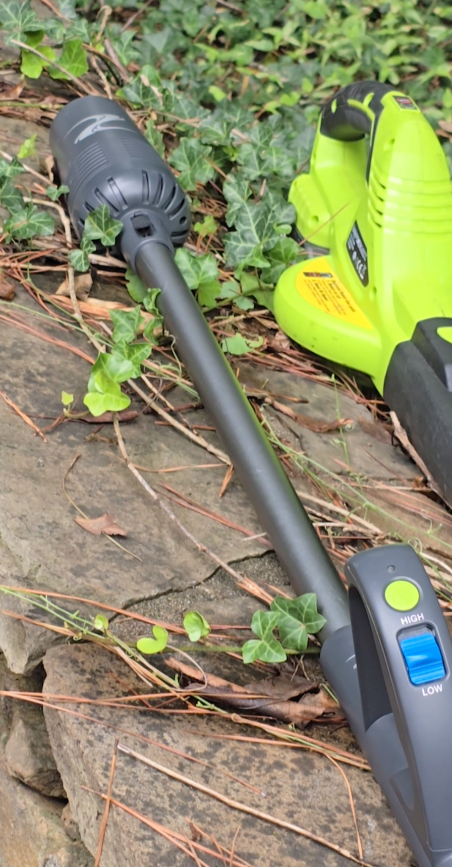 Gray cordless stick blower with a thin cone-like blower on one end and a handle with two large buttons on the other end.