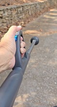 Load image into Gallery viewer, A person is holding the handle of a thin, gray stick blower. There is a blue button visible beneath their thumb, and we see the whole way down the device to the blowing end.
