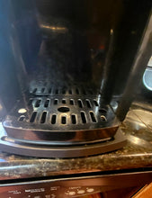 Load image into Gallery viewer, Close up of the drip tray of the coffee maker, underneath which the black caddy tray is visible.
