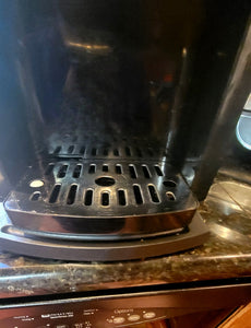 Close up of the drip tray of the coffee maker, underneath which the black caddy tray is visible.