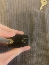 Load image into Gallery viewer, One end of the cable has been removed, showing the small hole in the black lock where it will be reinserted.
